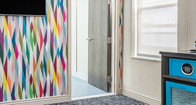 Standard Queenn Bed photo showing colorful room with a safe and microwave.