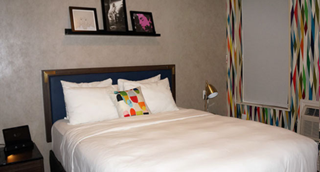 Full Bed Guest Room Full Bed Guest room showing full size bed, night stand, lamp, and Aavago communication device.